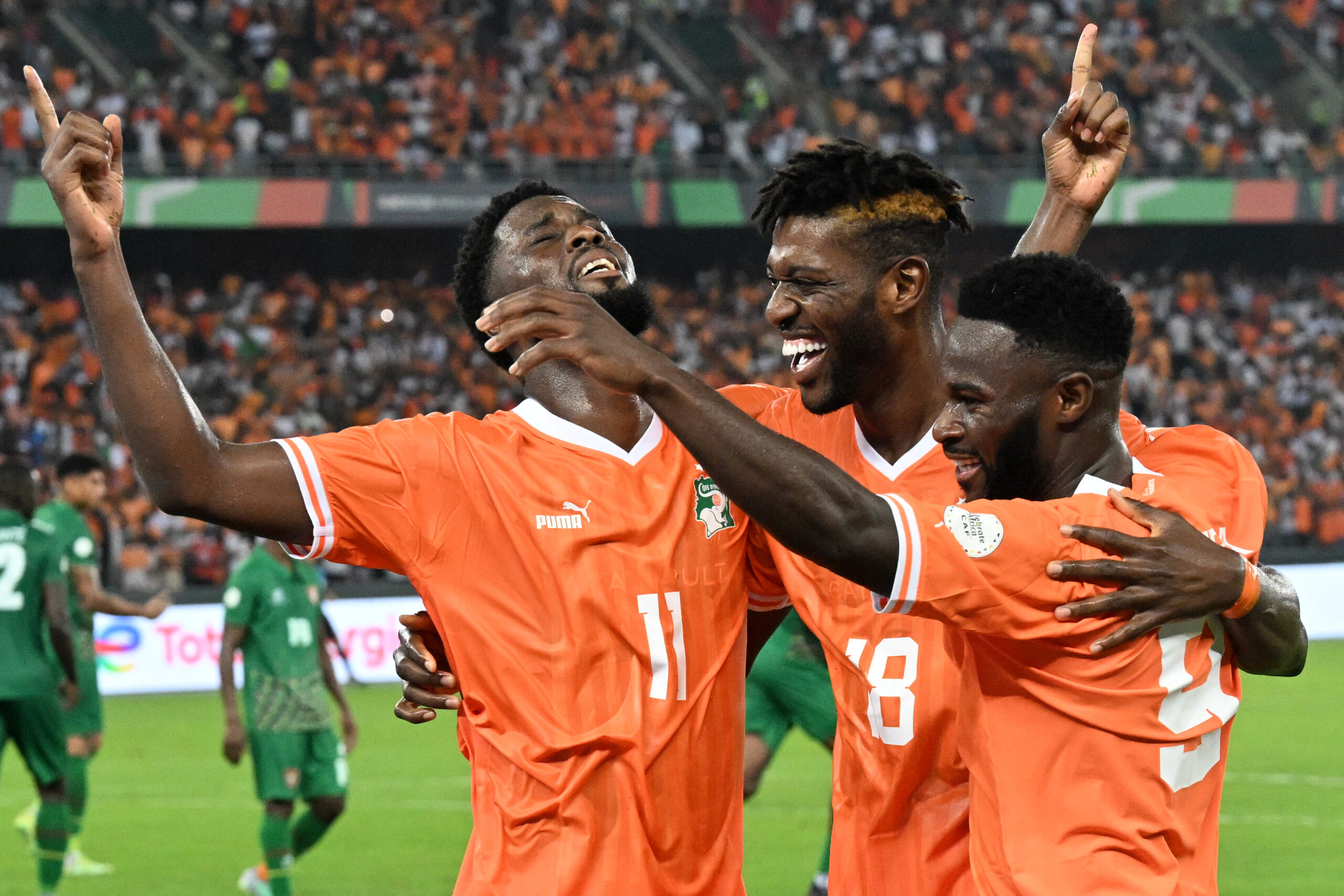 Ivory Coast's forward #11 Jean Philippe Nils Stephan Krasso celebrates with Ivory Coast's midfielder #18 Ibrahim Sangare and Ivory Coast's forward #9 Jonathan Bamba after scoring his team's second goal during the Africa Cup of Nations (CAN) 2024 group A football match between Ivory Coast and Guinea-Bissau at the Alassane Ouattara Olympic Stadium in Ebimpe, Abidjan, on January 13, 2024. (Photo by Issouf SANOGO / AFP) (Photo by ISSOUF SANOGO/AFP via Getty Images)