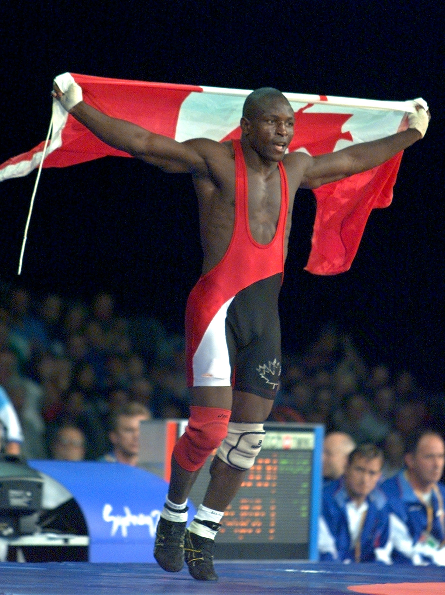 Daniel Igali of Canada waves the Canadian national flag following his gold medal victory over Russia's Arsen Gitinov in the final of the 69kg freestyle wrestling competition at the Syndey 2000 Olympic Games.